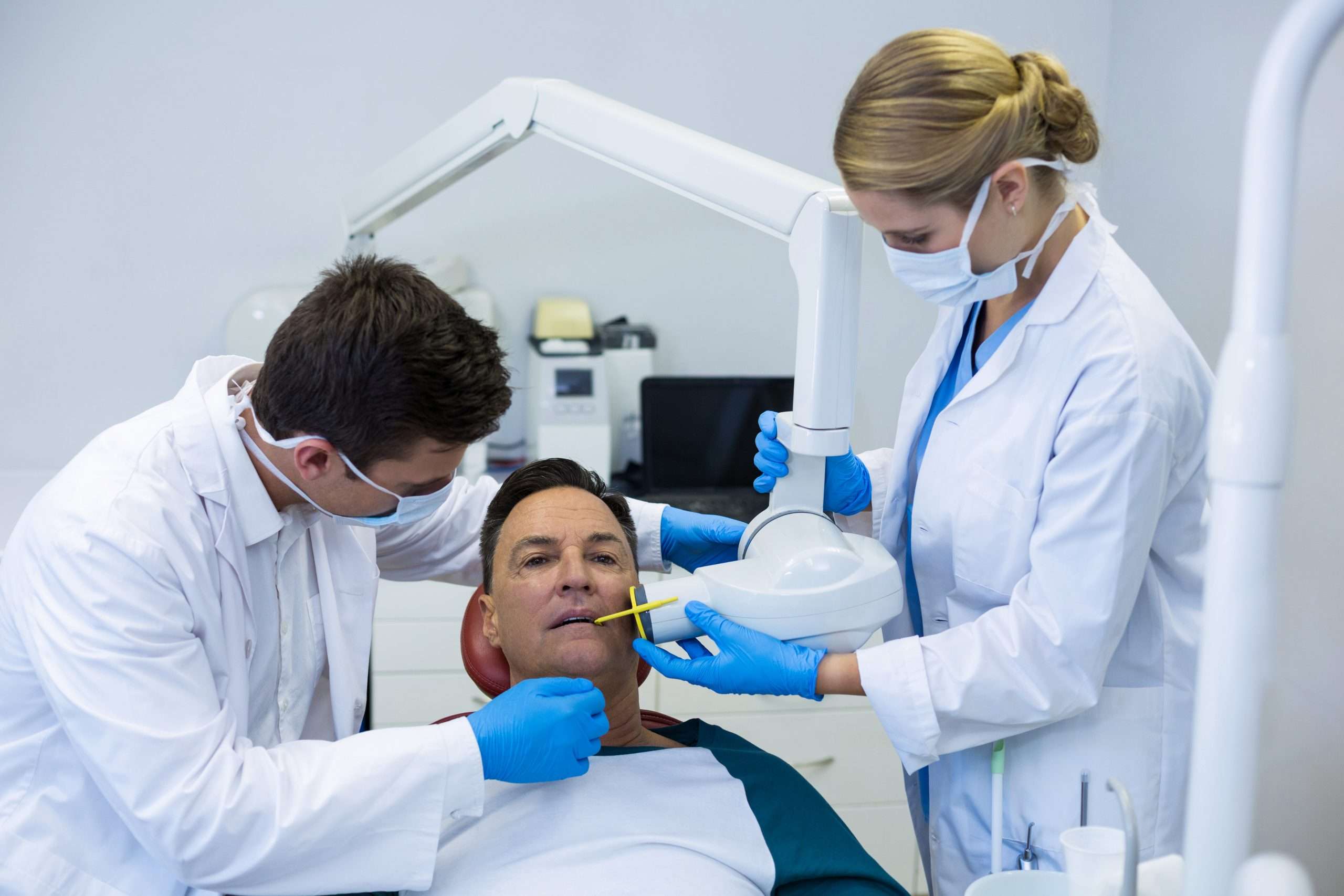 Dentists examining a male patient with tools